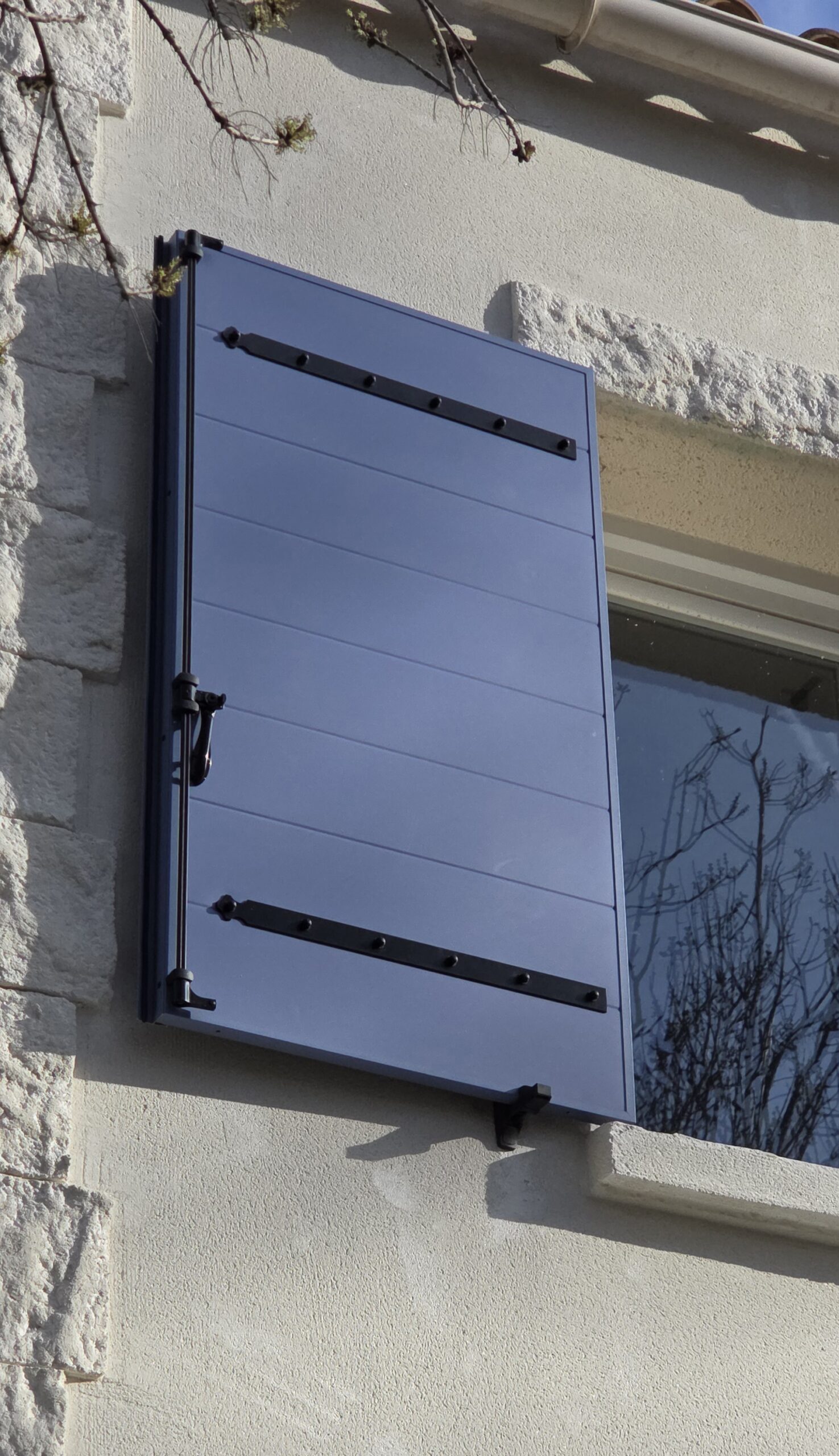 Détail d’un volet battant en aluminium isolé bleu RAL 5021 avec ferrures noires