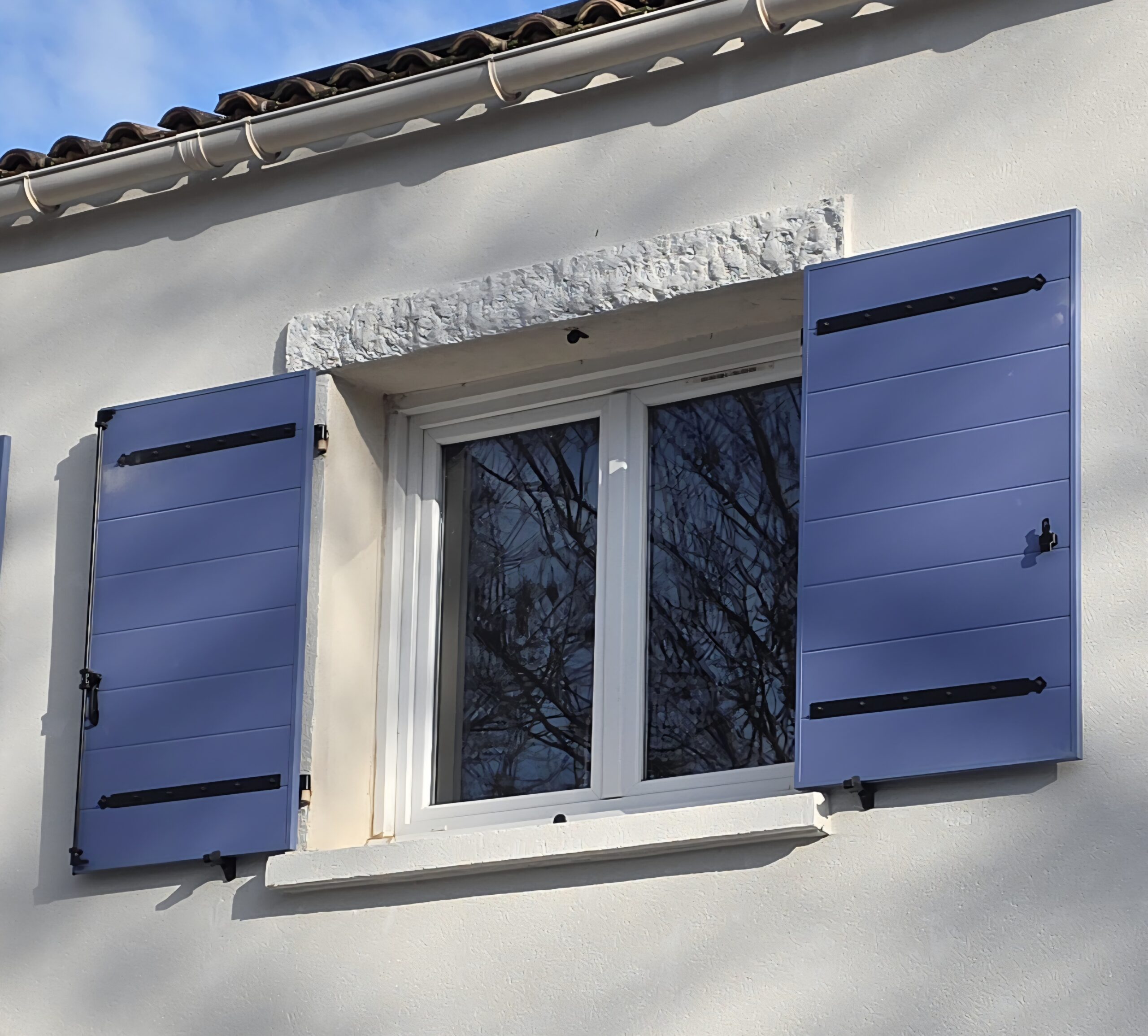 Volets battants aluminium isolés sur mesure installés sur une fenêtre de villa