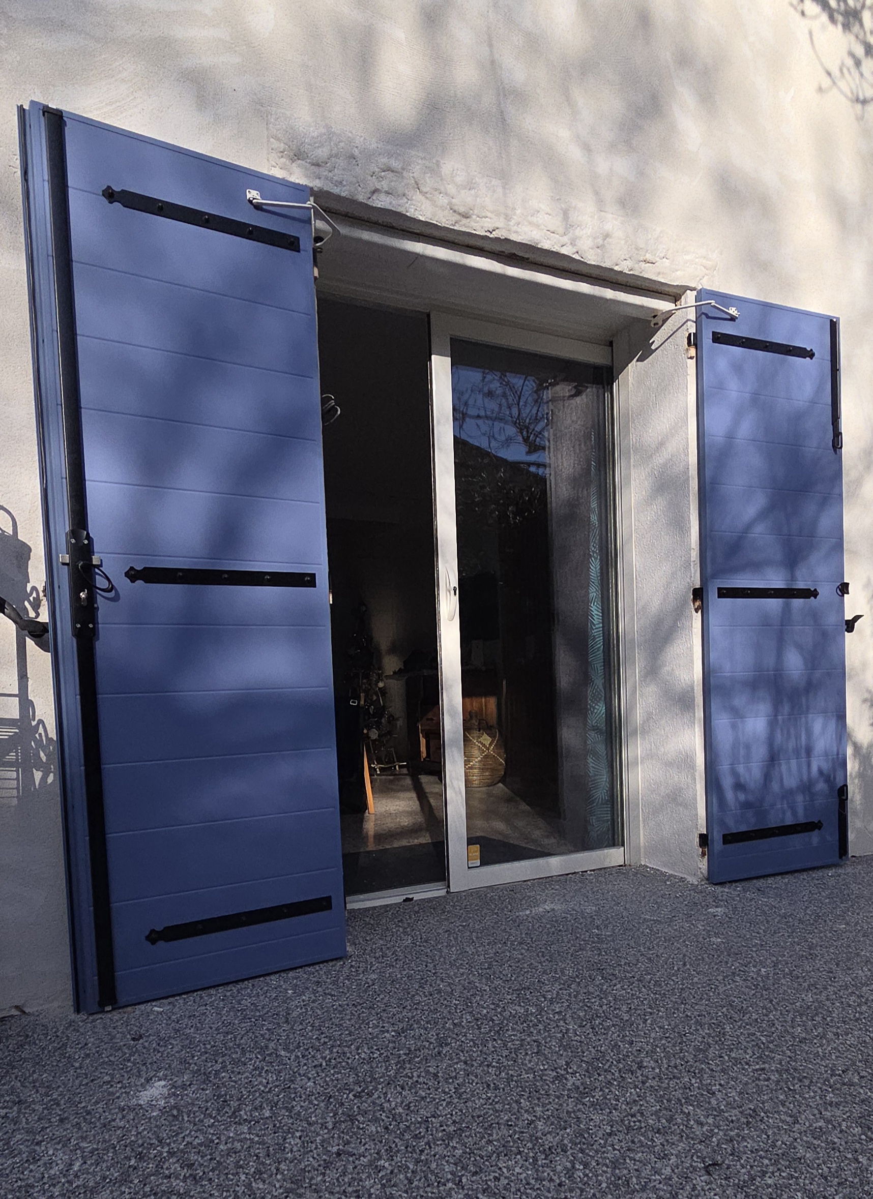 Volets battants aluminium ouverts sur une grande baie